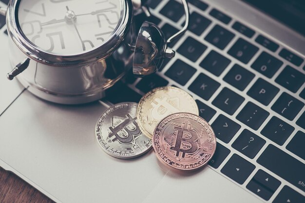 Photo high angle view of bitcoins with alarm clock on laptop