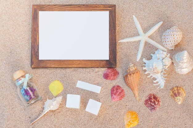 Photo high angle view of blank frame and seashell on sand at beach