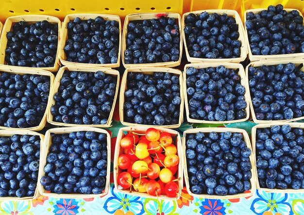 Photo high angle view of blueberry and cherry fruits for sale in market