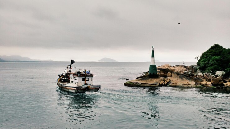 Фотография высокоугольный вид лодки в море по скальным образованиям на фоне неба