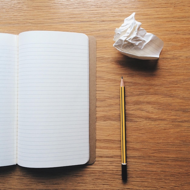 High angle view of book and pencil on wooden table