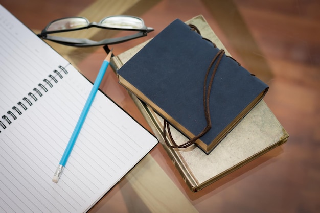 High angle view of books with pencil and eyeglasses on table