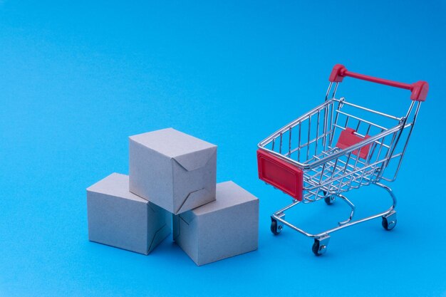 High angle view of box and shopping cart over blue background