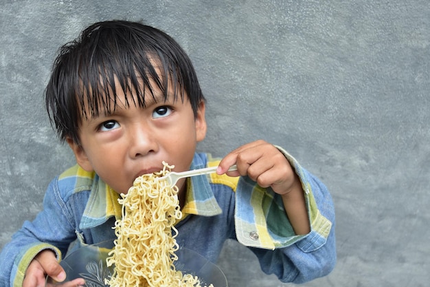 Photo high angle view of boy eating noodles against wall