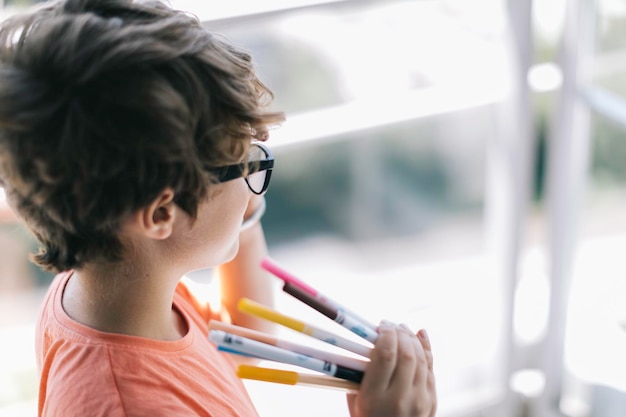 high angle view of boy holding colored pencils