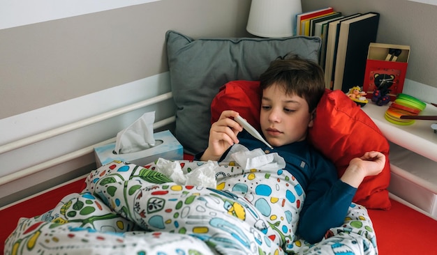 Photo high angle view of boy holding thermometer on bed at home