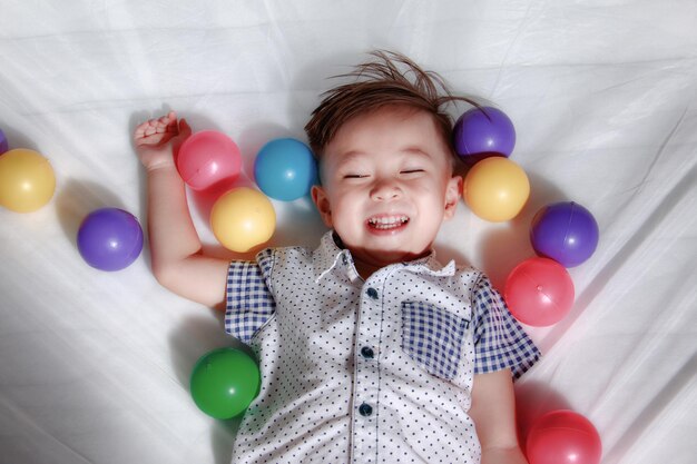 High angle view of boy playing with balloons while lying on bed at home