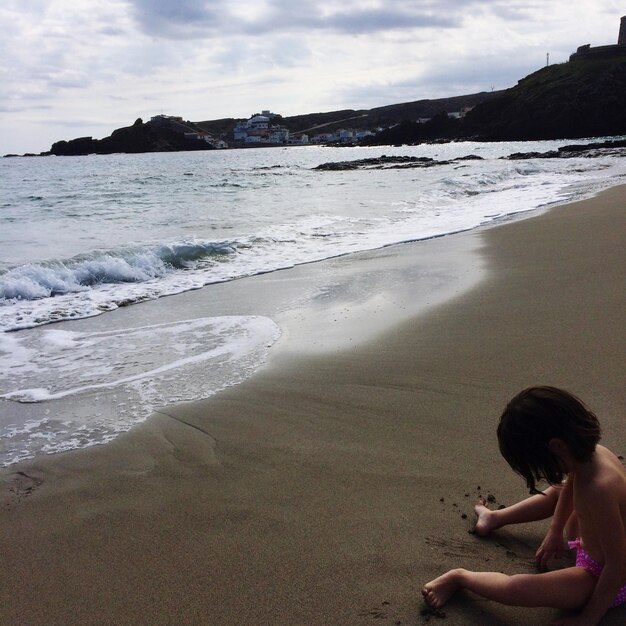 Foto vista ad alta angolazione di un ragazzo che gioca con la sabbia sulla riva alla spiaggia