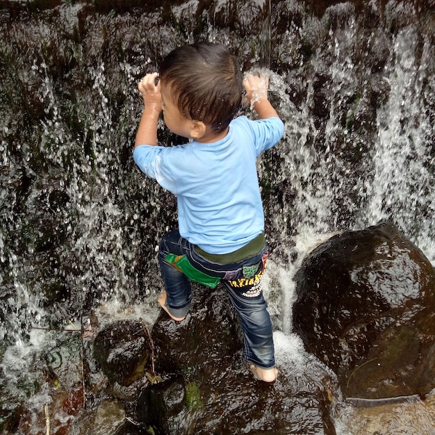 Photo high angle view of boy on rock at waterfall