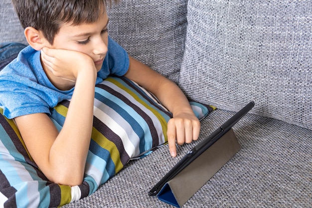 High angle view of boy using digital tablet while lying on sofa