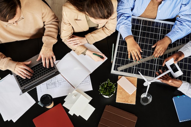 High angle view of business colleagues working with equipments\
of alternative energy at table during