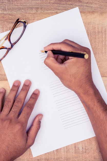 High angle view of businessman writing on paper at desk in office