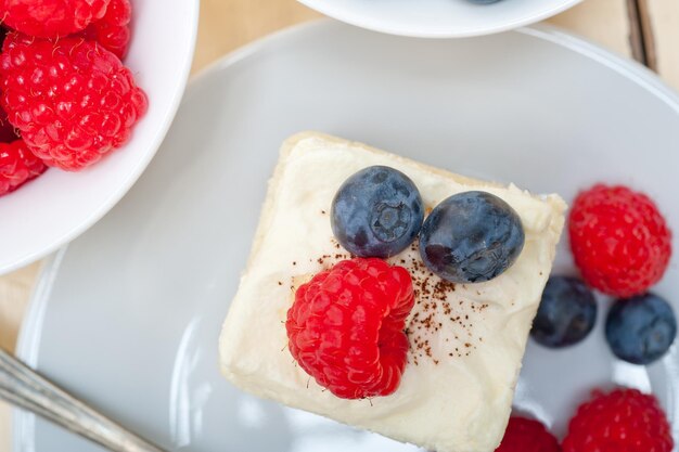 High angle view of cake with raspberries and blueberries in plate on table