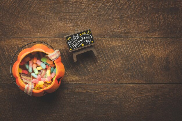 Высокоугольный вид конфет в фонаре Джека О на столе во время Хэллоуина