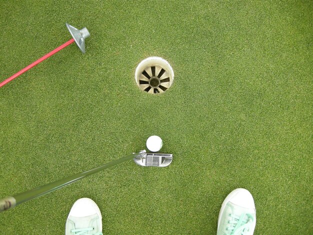 Photo high angle view of canvas shoes and golf club by hole at course