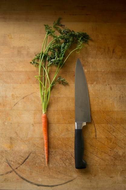 Foto vista ad alto angolo di carota e coltello su un tavolo di legno in cucina a casa