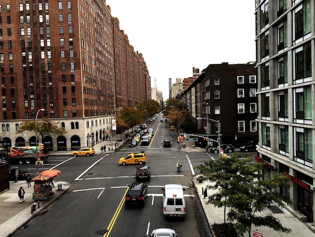 High angle view of cars on road amidst buildings against clear sky