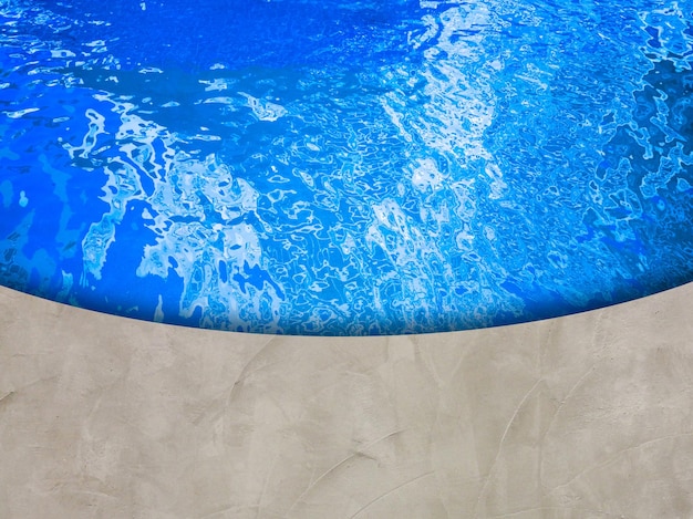 High angle view of cement floor. above is a bright blue\
pool.