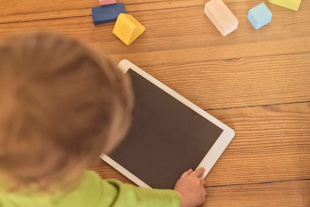 Photo high angle view of child using digital tablet on hardwood floor