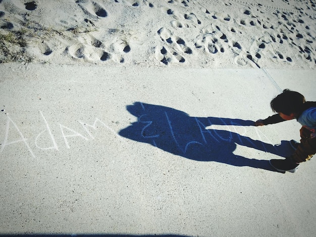 Foto vista ad alta angolazione della scrittura del bambino con il gesso sulla passerella sulla spiaggia