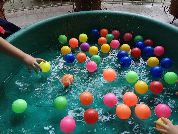 Photo high angle view of children playing with balls floating on water in container