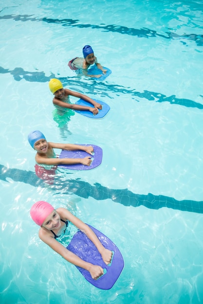 High angle view of children using kickboard while swimming in pool