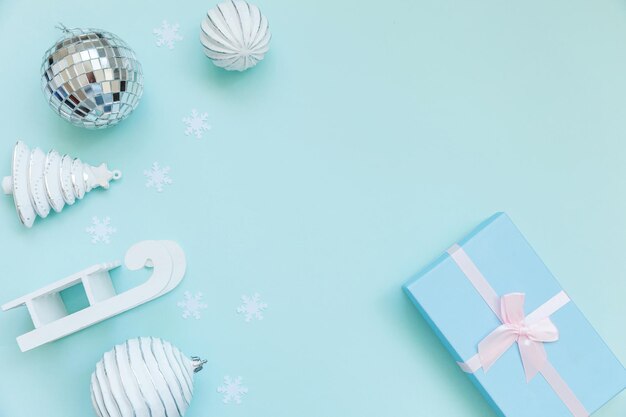 High angle view of christmas ornament with disco ball by gift over blue background