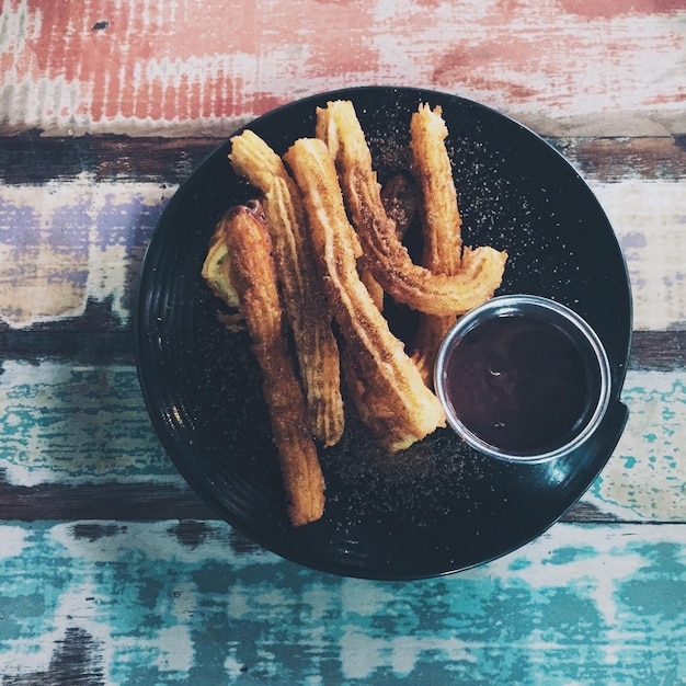 Photo high angle view of churros and hot chocolate in plate on table
