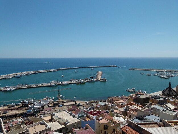 High angle view of city by sea against clear sky