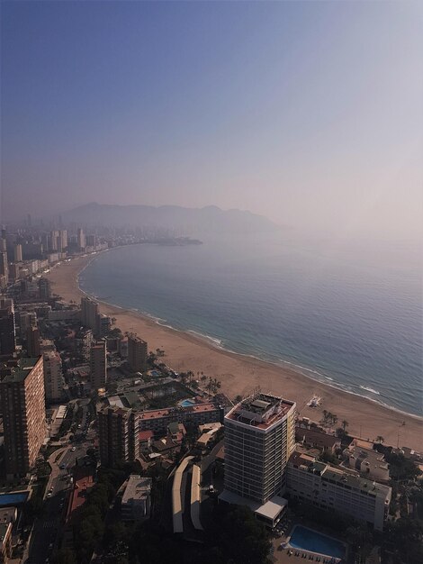 High angle view of cityscape by sea against clear sky