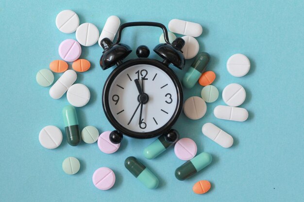 High angle view of clock and pill on table