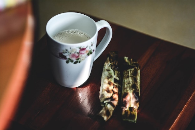 Foto vista ad alto angolo della tazza di caffè e del cibo avvolto in foglia sul tavolo