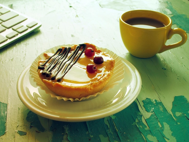 Photo high angle view of coffee cup and tart with computer keyboard on wooden table