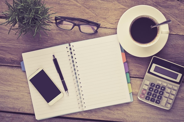 high angle view of coffee cup with mobile phone and diary on wooden table