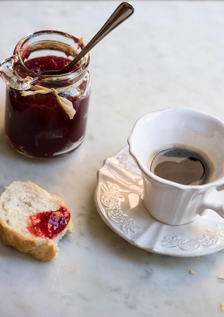 Foto vista ad alta angolazione del caffè e della marmellata di fragole con la baguette sul tavolo