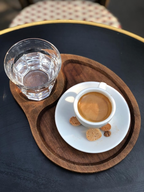 テーブルの上の木製のトレイにコーヒーと水の高角度のビュー