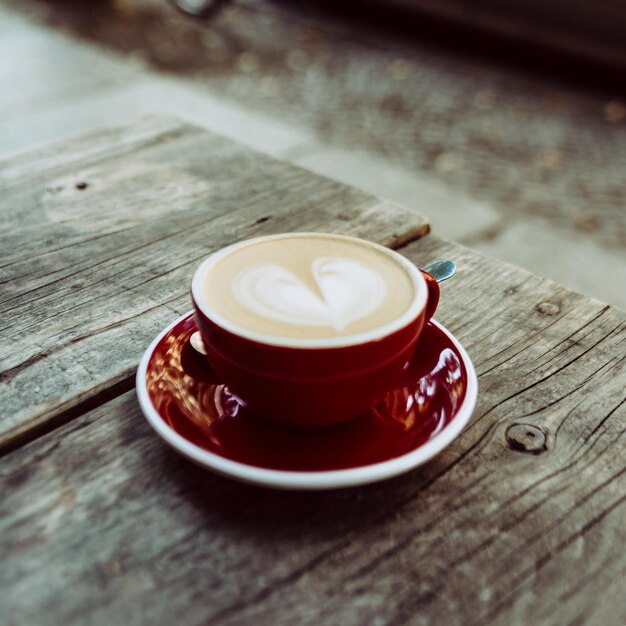 high angle view of coffee with heart shape froth art on wooden table