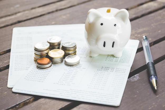 Photo high angle view of coins with piggy bank and bank books on table