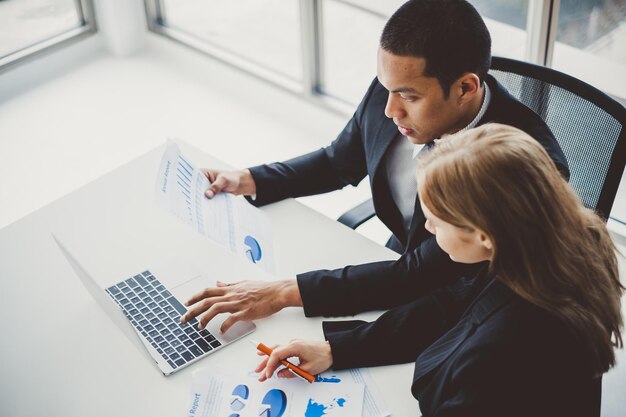 High angle view of colleagues analyzing graphs on laptop at office desk