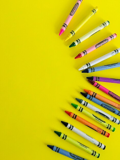 High angle view of colored pencils against yellow background