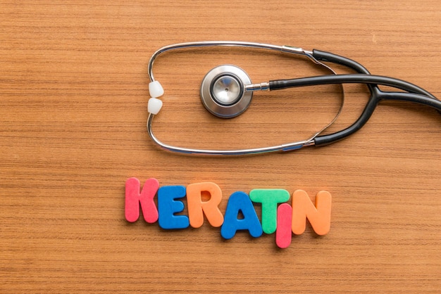 High angle view of colorful keratin text with stethoscope on wooden table