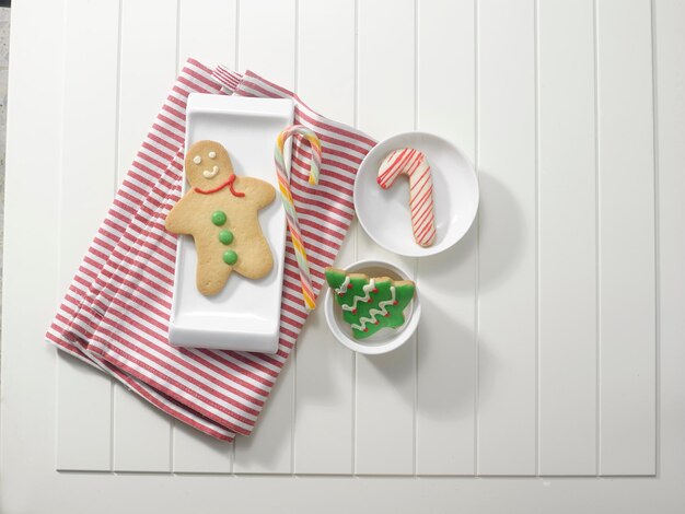 Photo high angle view of cookies in plate with napkin and candy cane on table