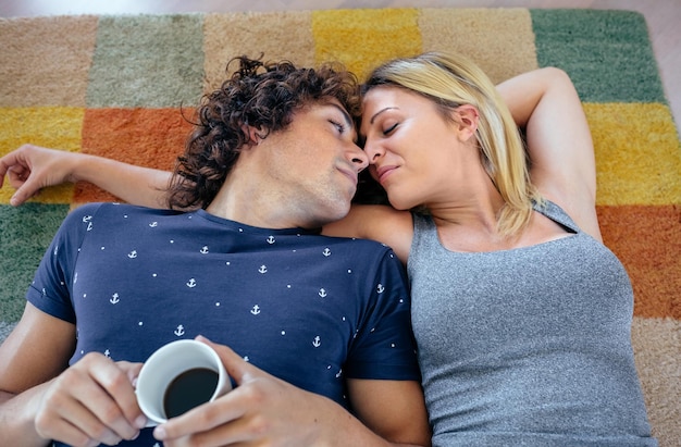 Photo high angle view of couple romancing while lying on carpet