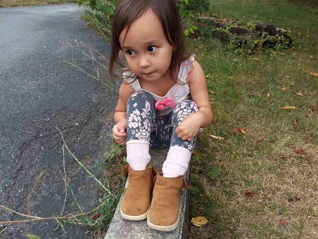 High angle view of cute girl sitting on retaining wall