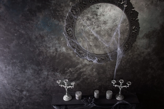 High Angle View of Decorative Round Frame Above Candles and Candelabras on Eerie Cobweb Covered Mantle in Haunted House Setting