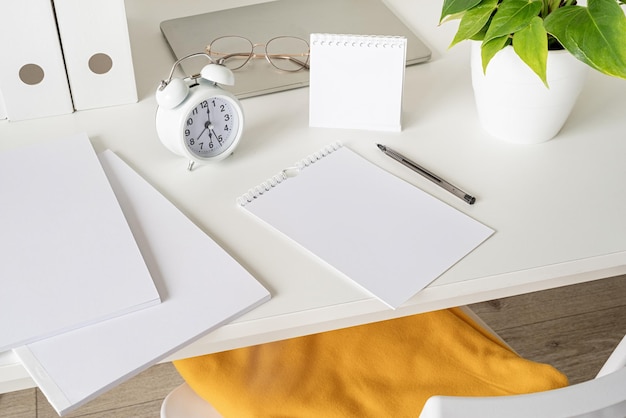 High angle view of desk arrangement with two blank calendars\
for mock up, magazines and stationery