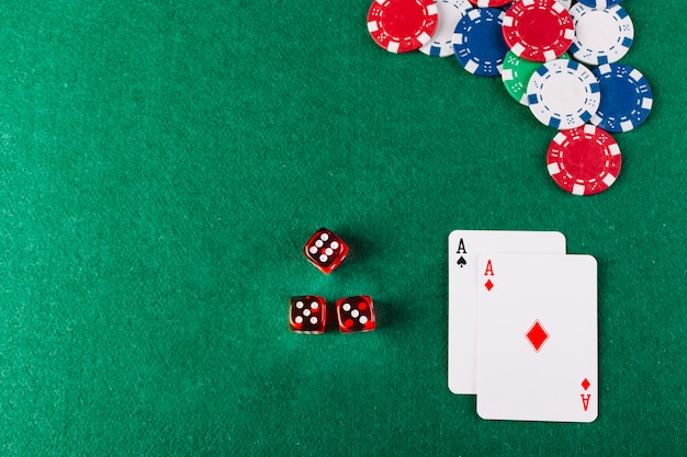 High angle view of dice; chips and ace playing cards on poker table