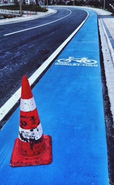 High angle view of dirty traffic cone on blue bicycle lane