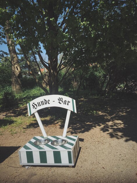 Photo high angle view of dog bowls with text on ground against trees