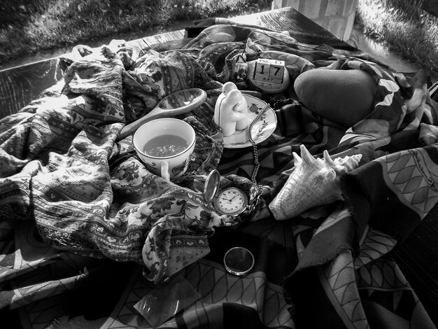 Photo high angle view of drink and pocket watch on messy bed